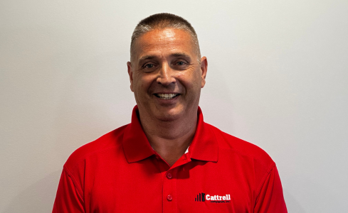 Smiling person in a red polo shirt standing against a plain background.