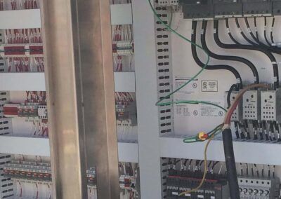 Electrical control panel with wires, breakers, and terminal blocks inside an open cabinet.