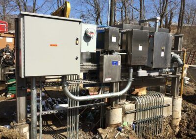 Outdoor industrial electrical equipment with metal cabinets, pipes, and conduit in a wooded area