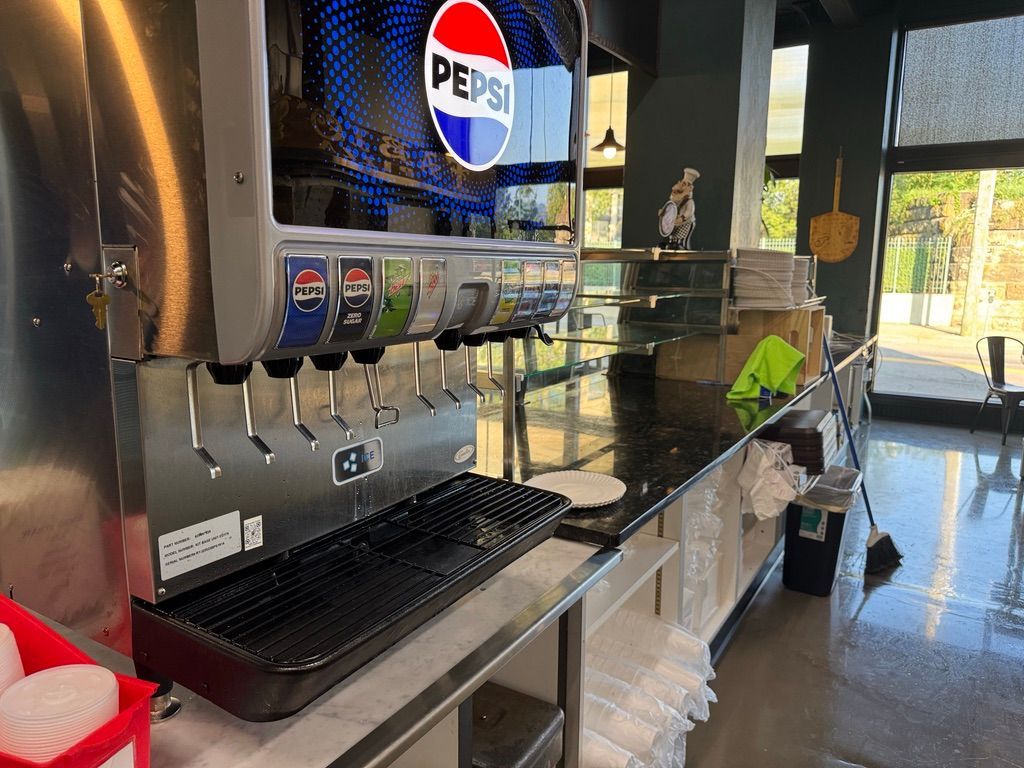 Pepsi soda fountain with multiple dispensers and cups on a counter in a bright store