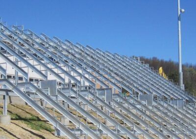 Empty silver bleachers under a clear blue sky at an outdoor stadium