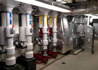 Industrial room with pipes, valves, and insulated ductwork in a basement mechanical area