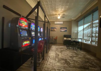 Slot-machine lounge with red chairs, patterned carpet, and large windows in a dimly lit room