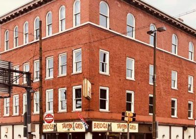 Red brick corner building with storefronts and arched windows on a city street corner