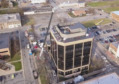Aerial view of a downtown office building with surrounding streets, parking lots, and nearby low-rise buildings