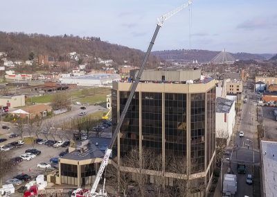 Downtown building under construction with a crane and surrounding streets, seen from above