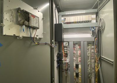 Electrical control panel room with open cabinet, wiring, and circuit boards inside a metal enclosure.