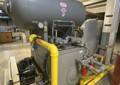 Large industrial boiler with yellow pipes and gauges in a utility room
