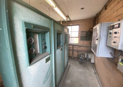 Industrial electrical room with green switch cabinets, control panels, and a small window