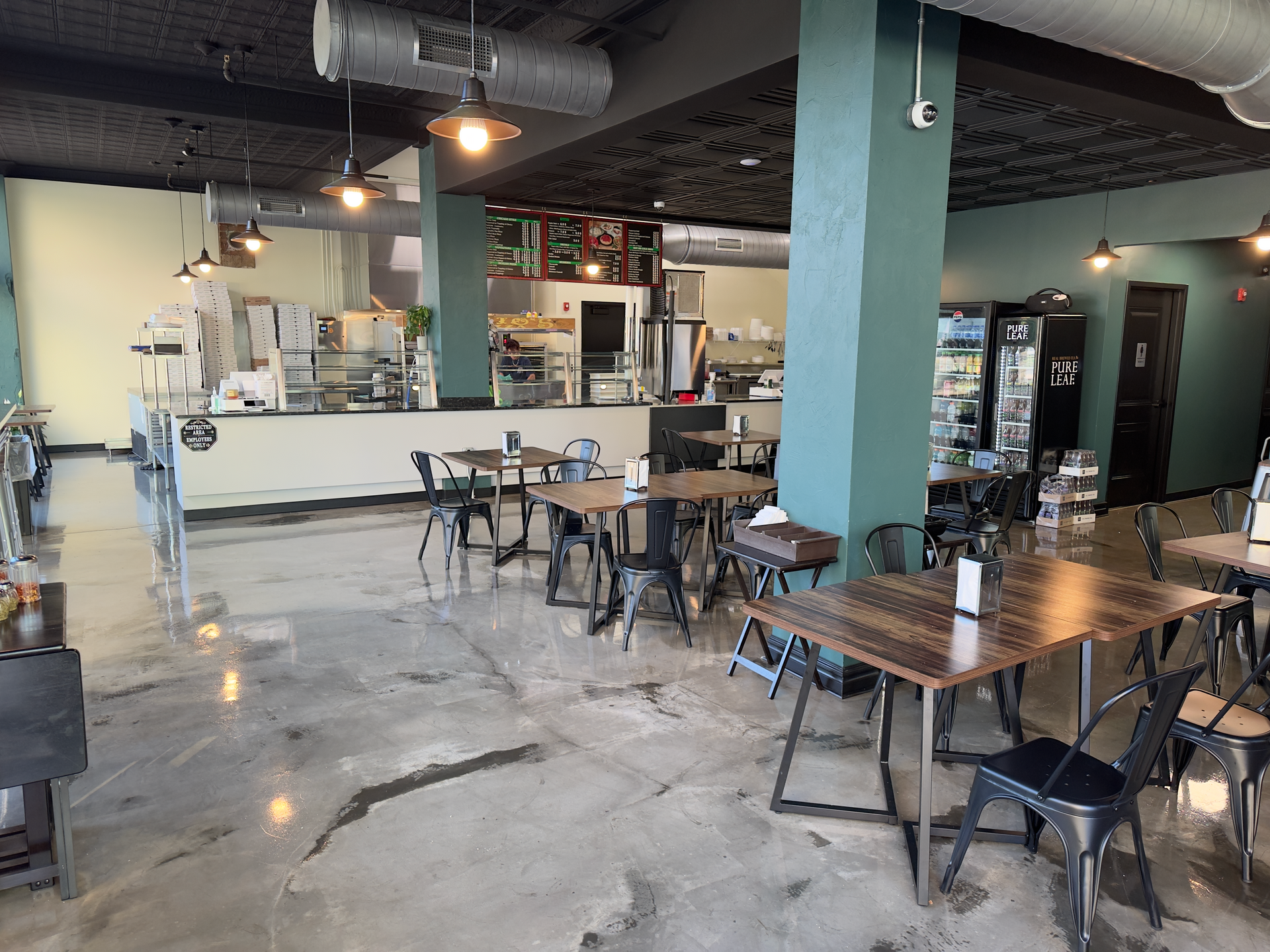 Empty café interior with tables, chairs, and a counter under exposed ceiling beams
