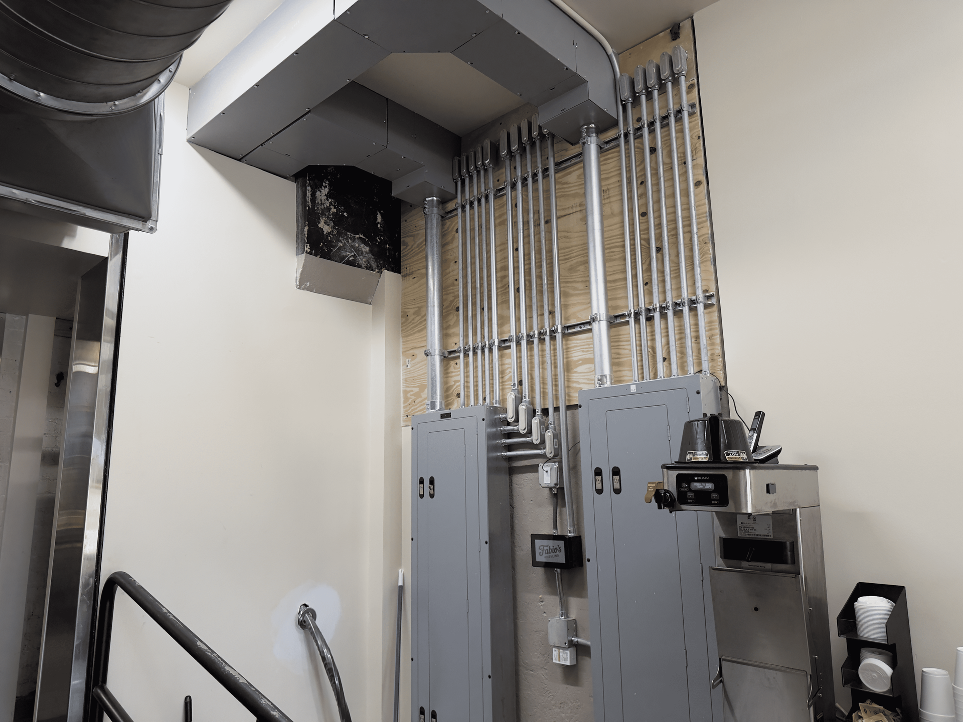 Industrial electrical panels and exposed conduit on a beige wall in a utility room