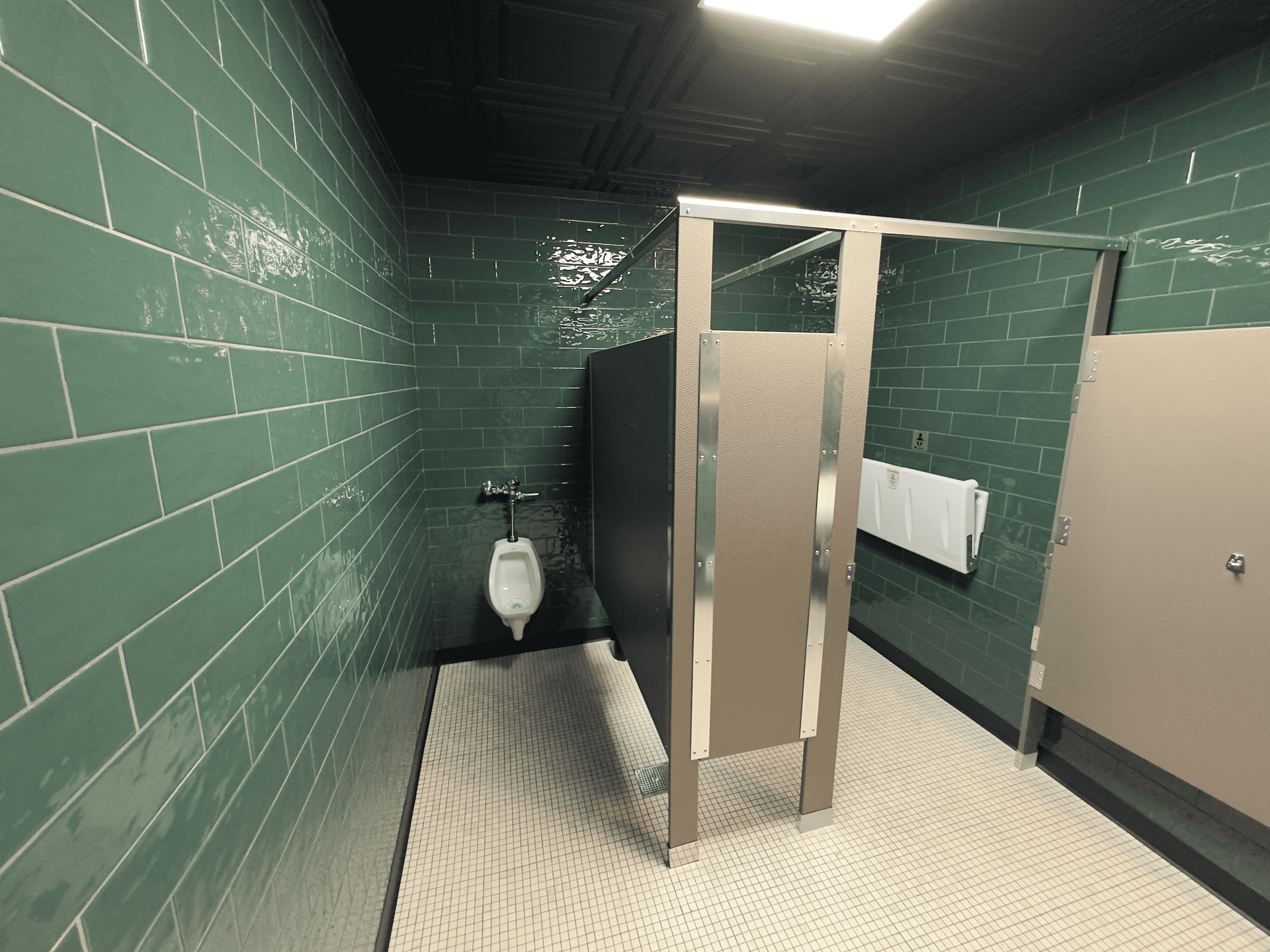 Public restroom stall with green tile walls, white toilet, and black-and-white checkered floor.