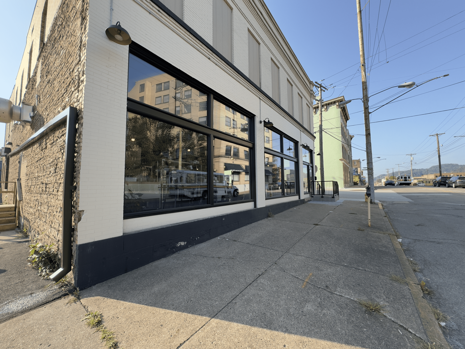 Street corner with a storefront, large windows, and a sidewalk under clear daylight.