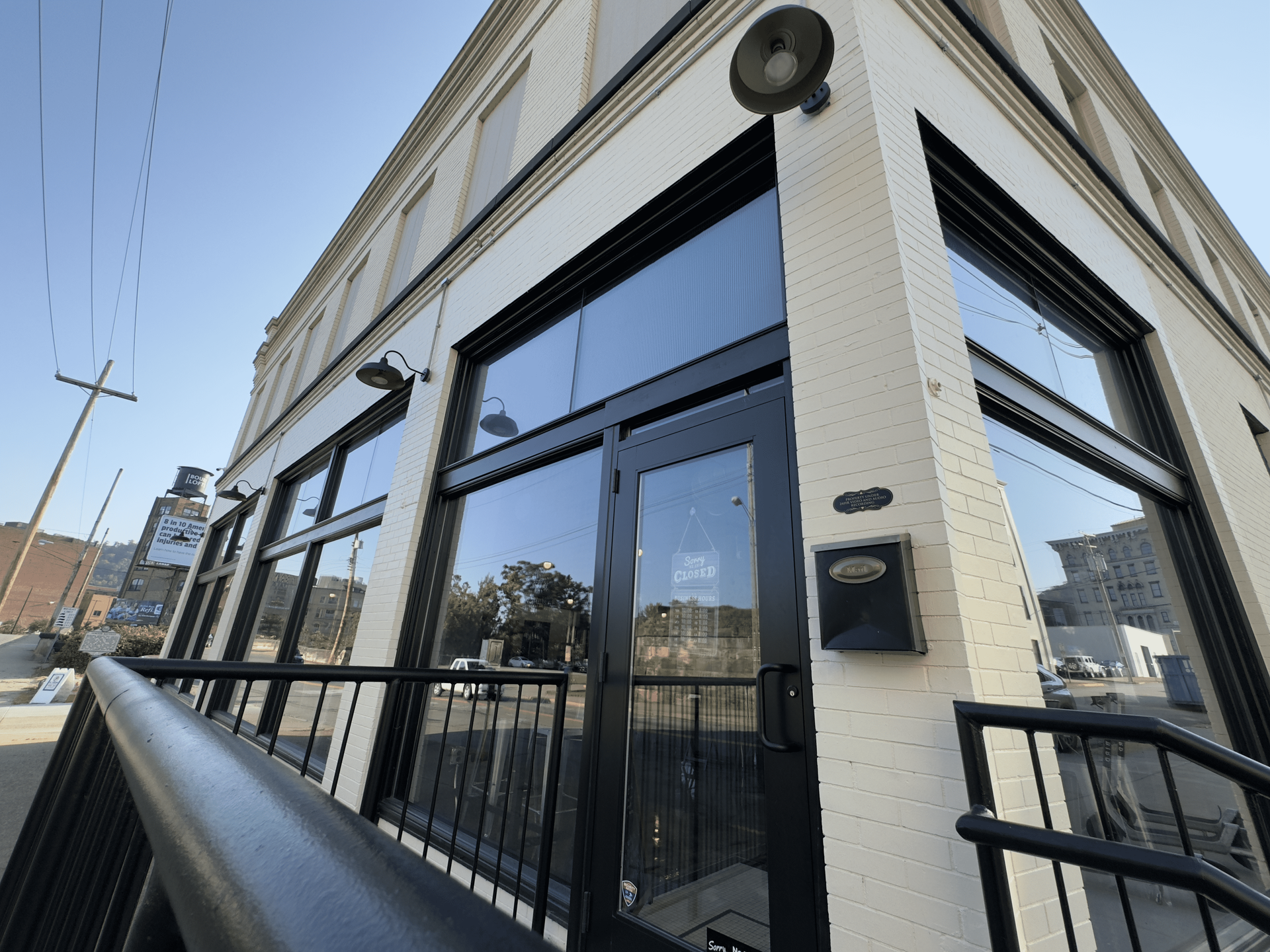 Corner storefront with dark blue awning, glass doors, and black railing on a street corner