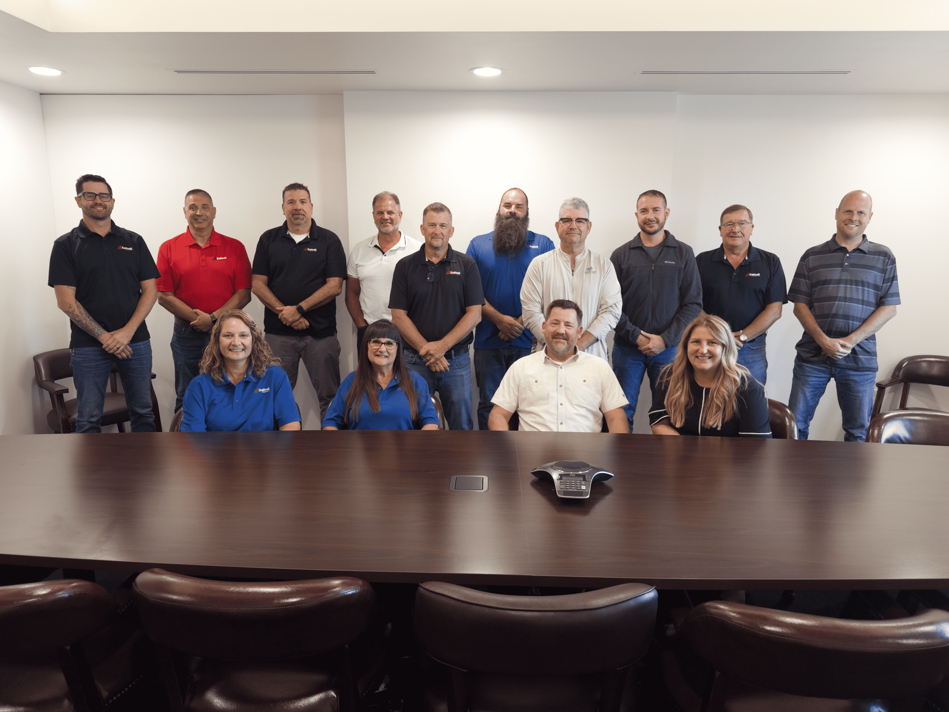 Group of people posing in a conference room behind a long meeting table