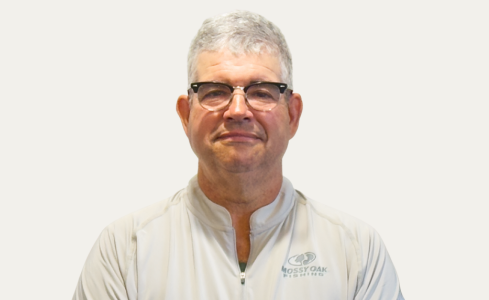 Portrait of a smiling person in glasses wearing a white shirt against a light background
