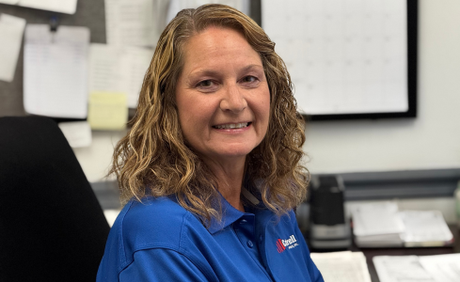 Smiling woman in a blue polo shirt seated in an office setting