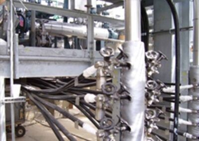 Industrial pipes and valves with black cables in a metal factory setting
