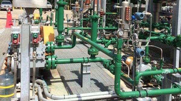 Green industrial piping and valves in a mechanical plant area.