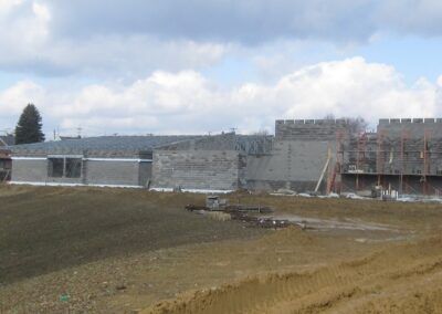 Partially built concrete building on a muddy construction site under a cloudy sky