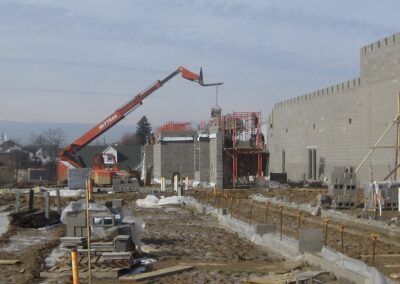 Construction site with a red crane beside unfinished concrete buildings and debris-covered ground