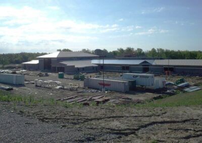 Industrial site with shipping containers and a large warehouse under a cloudy sky