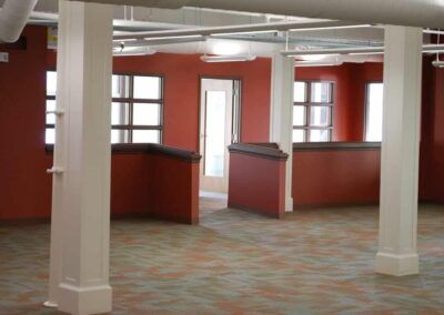 Empty office space with orange walls, white columns, and carpeted floor
