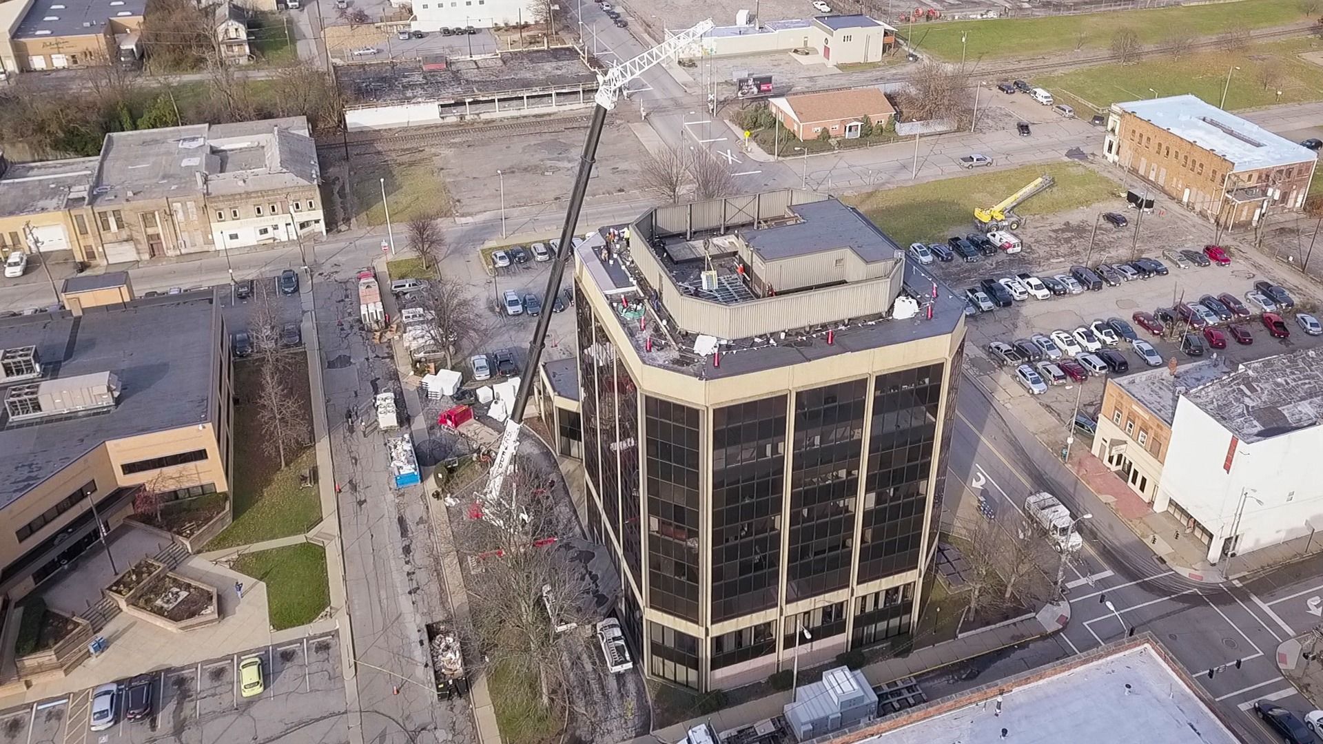 Aerial view of a downtown intersection with a tall black office building and surrounding streets, cars, and buildings.