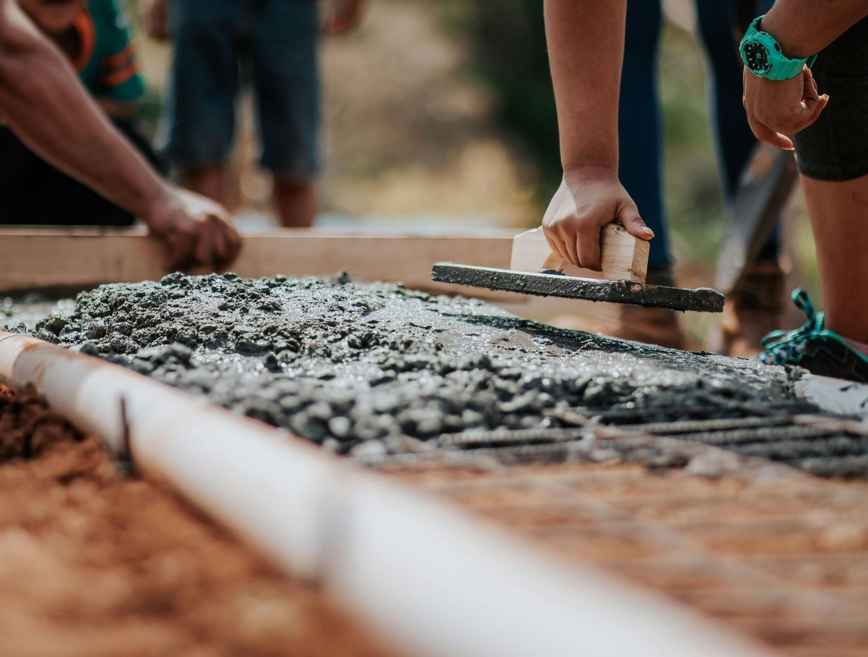 Workers smoothing wet concrete in a construction form outdoors