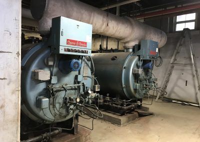 Industrial boiler room with large blue and gray machinery and pipes indoors
