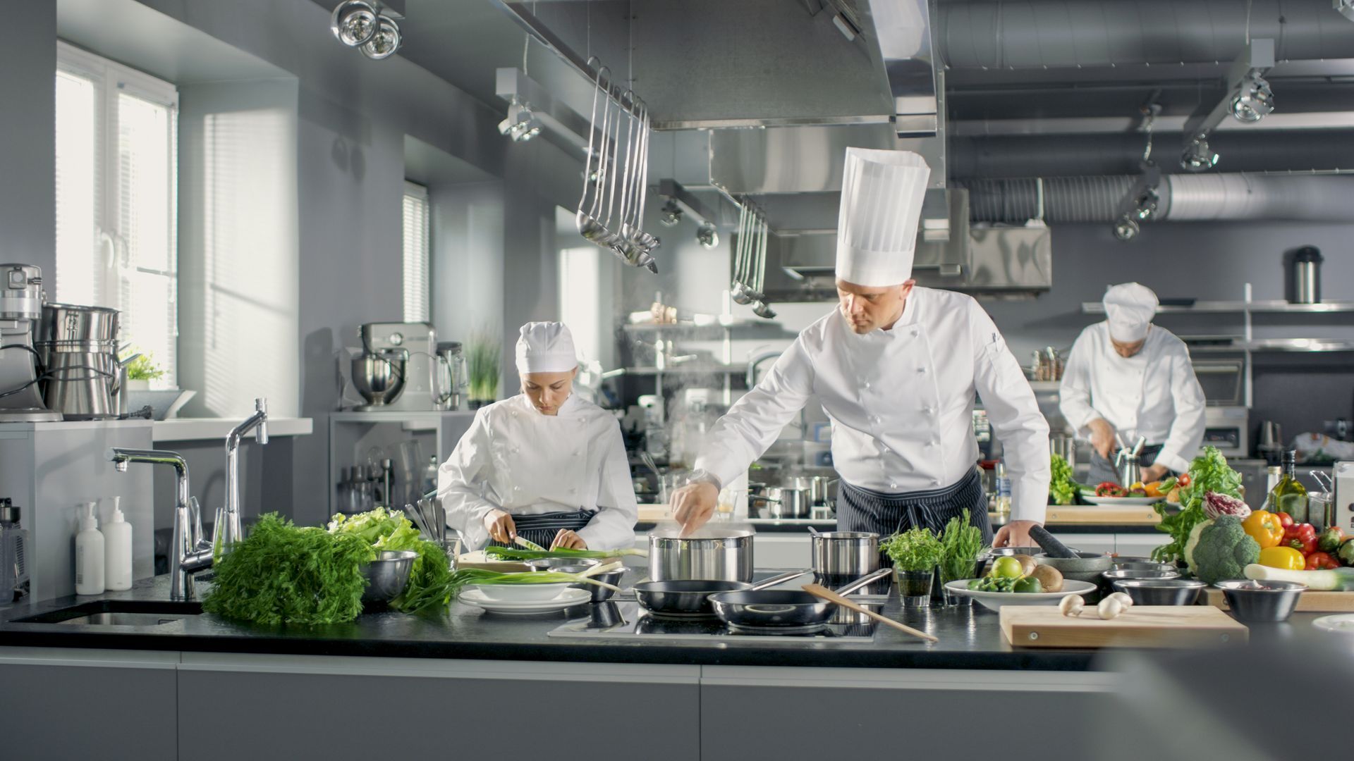 Haubenkoch mit Team in der Küche bei der Arbeit