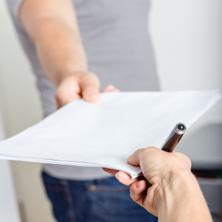 A person holding a pen and a piece of paper