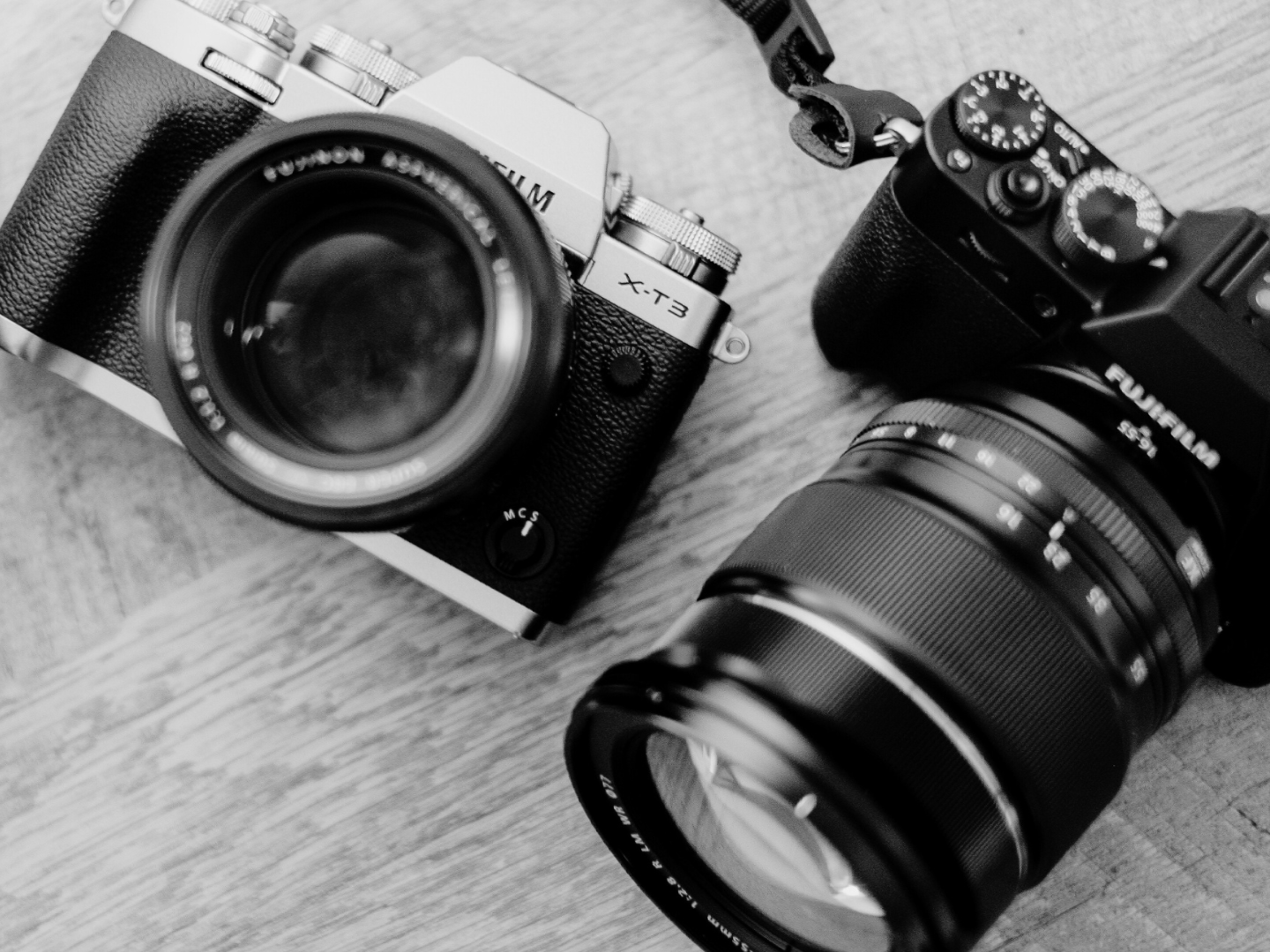 A black and white photo of two fujifilm cameras