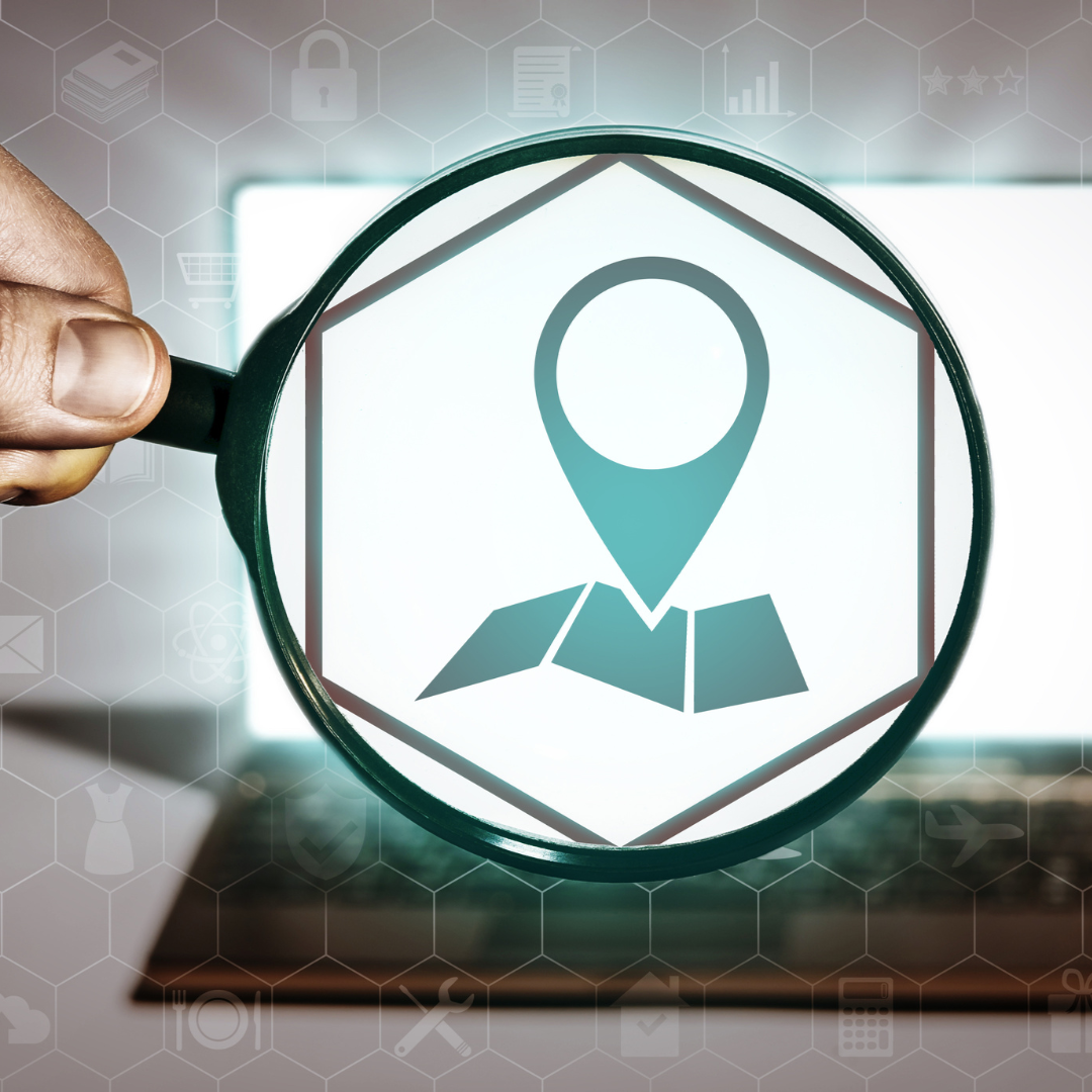 A person is holding a magnifying glass in front of a laptop
