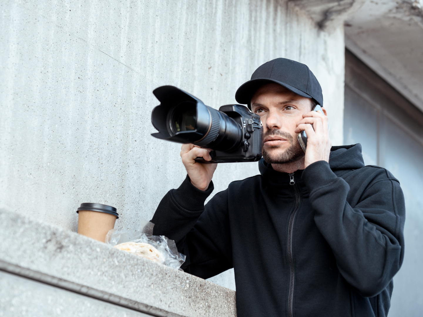 A man is holding a camera and talking on a cell phone.