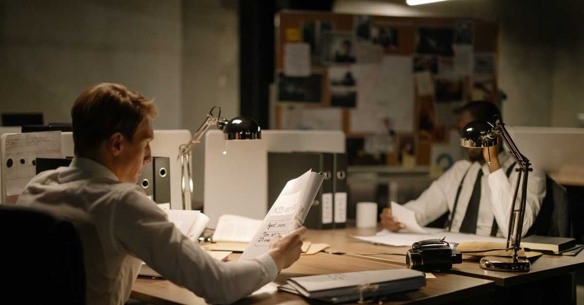 A man is sitting at a desk in an office looking at a piece of paper.