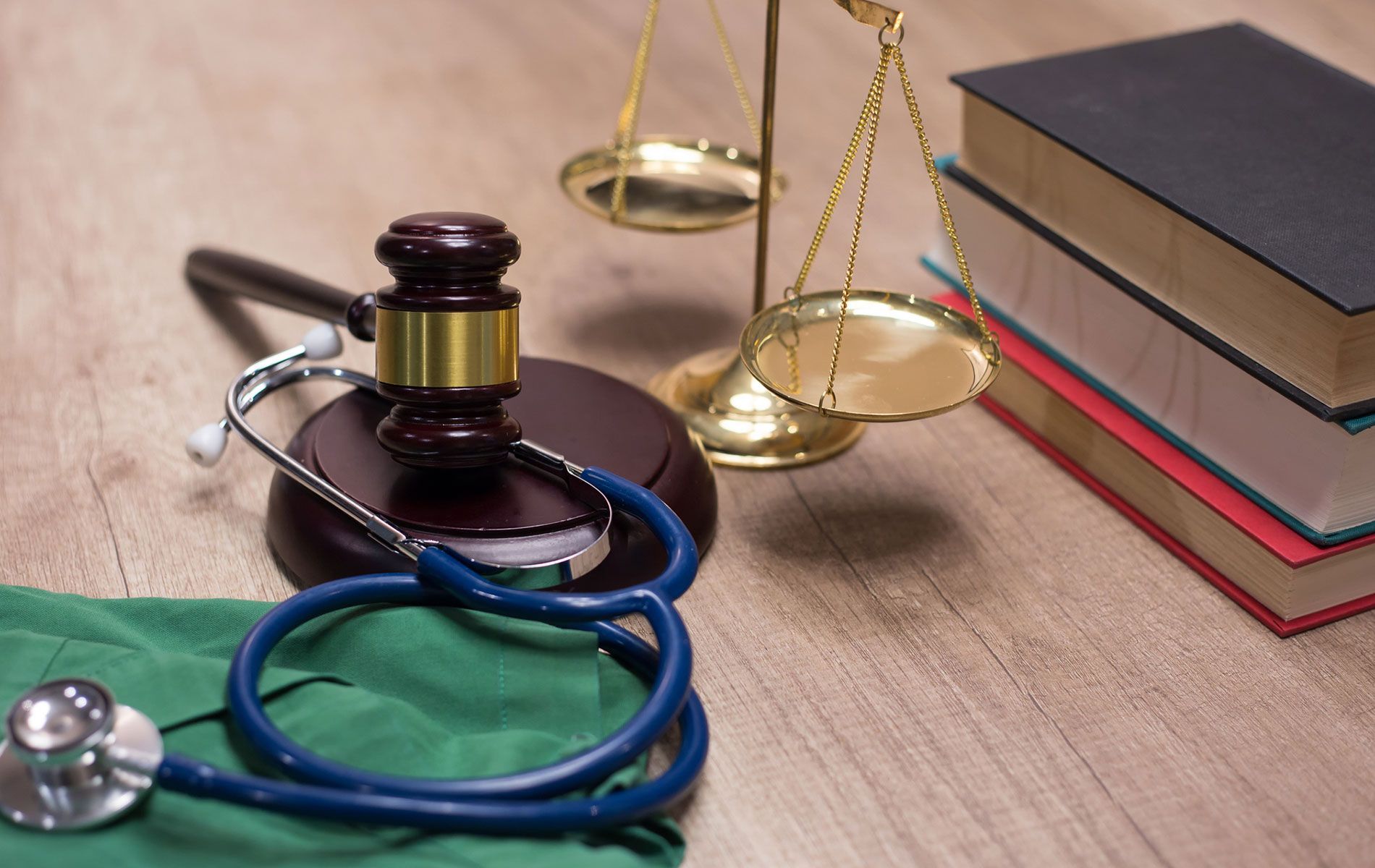 A stethoscope , scales of justice , and books are on a wooden table.