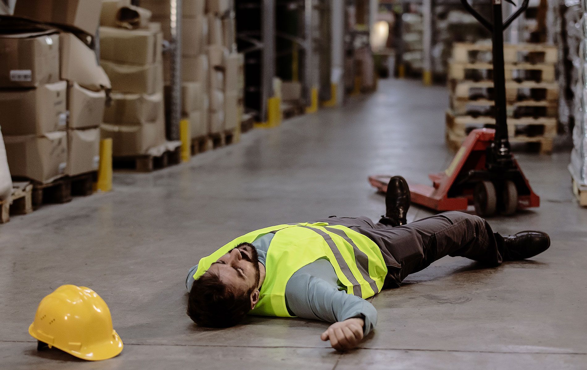 A man is laying on the floor in a warehouse.