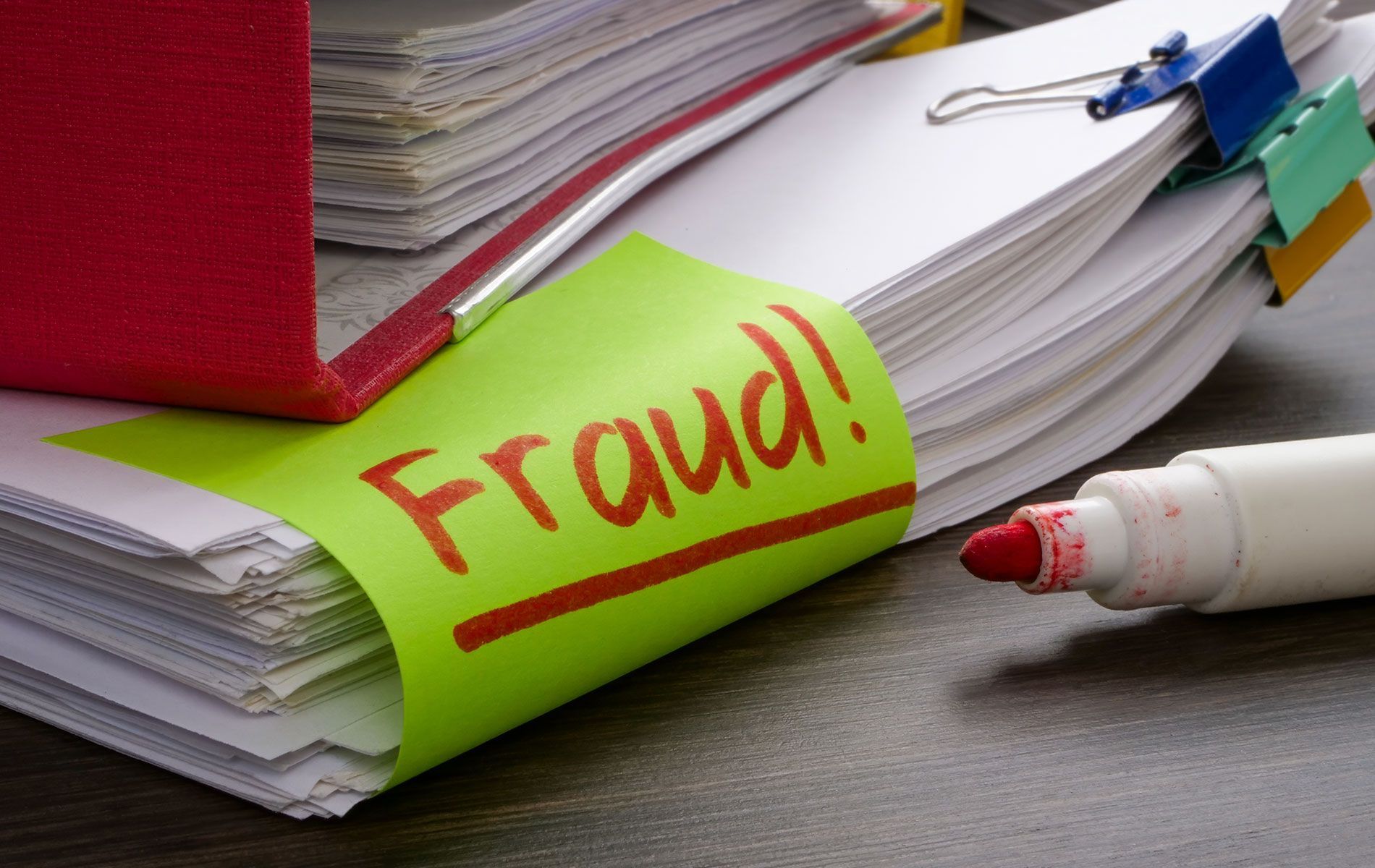 A yellow sticky note with the word fraud written on it