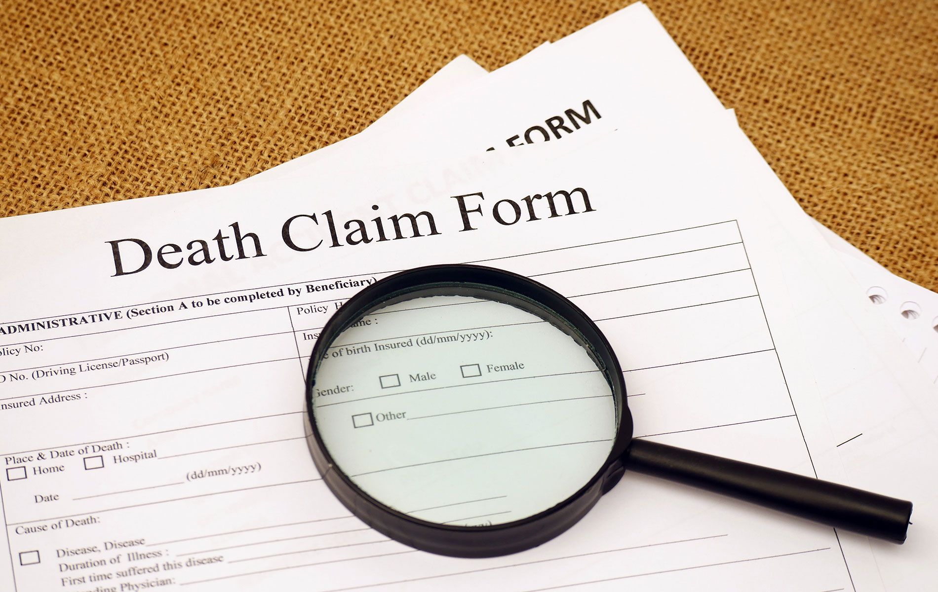 A paper of a death claim form with the magnifying glass on it