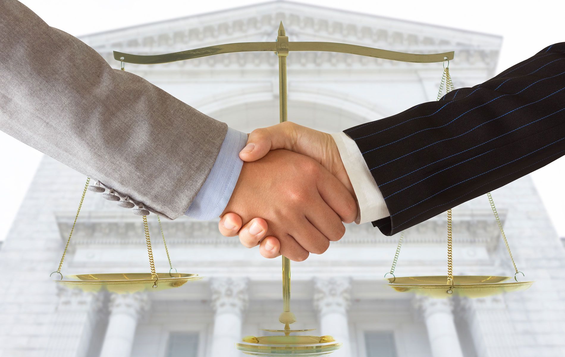 Two people shaking hands in front of a scale of justice