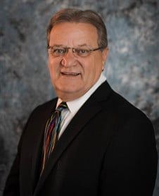 a man in a suit and tie is smiling for the camera .