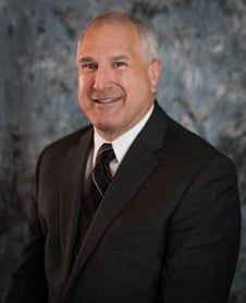 a man in a suit and tie is smiling for the camera .