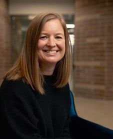 a woman is smiling for the camera while wearing a black sweater .