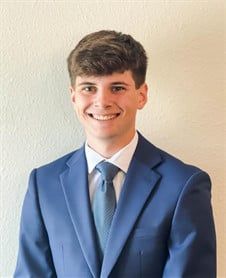 a young man in a suit and tie is smiling for the camera .