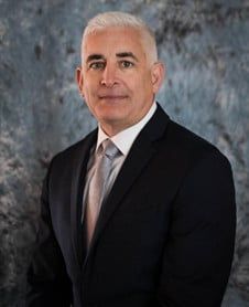 a man in a suit and tie is standing in front of a blue background .