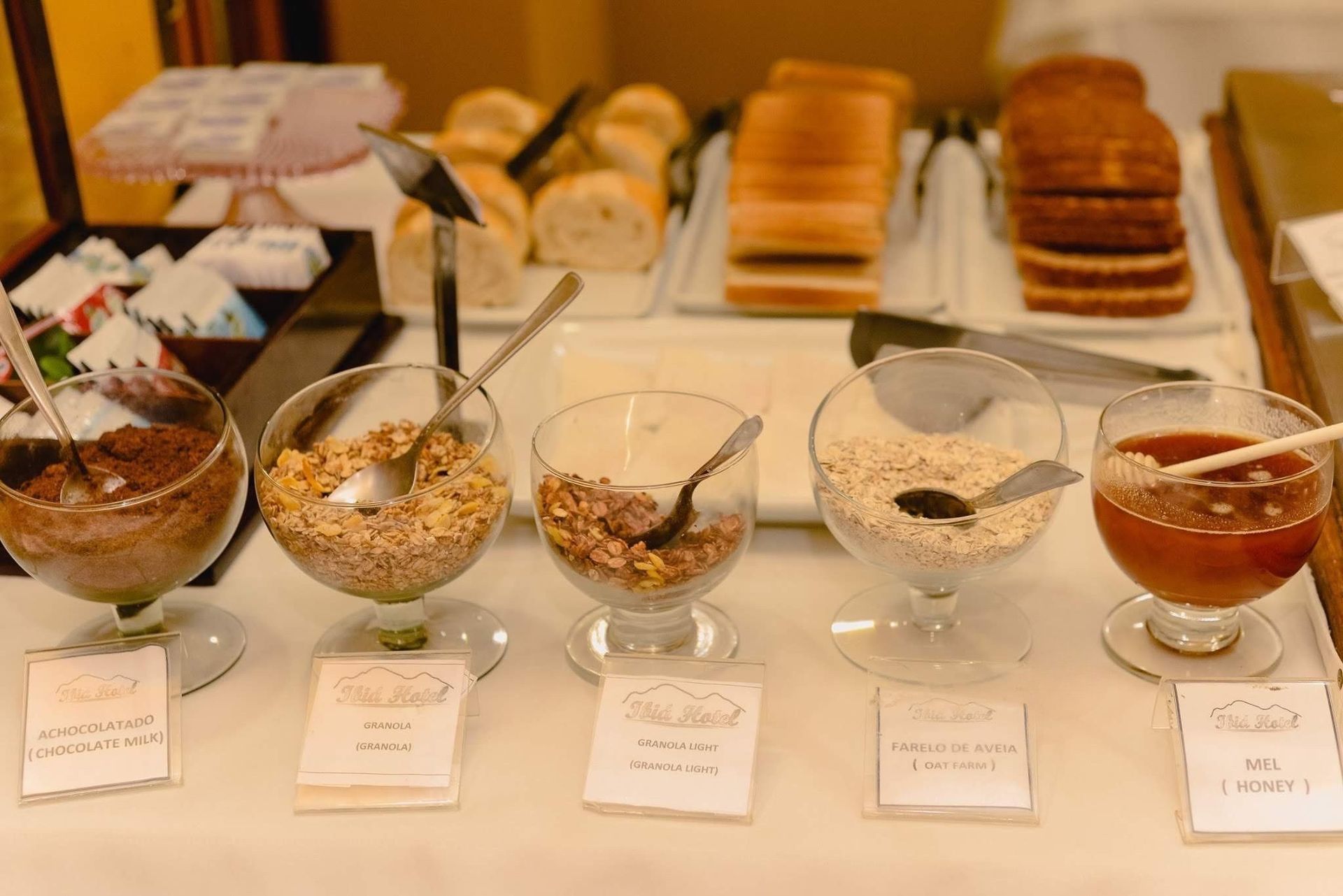 Tigelas com uma variedade de sobremesas e doces em uma mesa de buffet, cada uma com sua respectiva etiqueta.