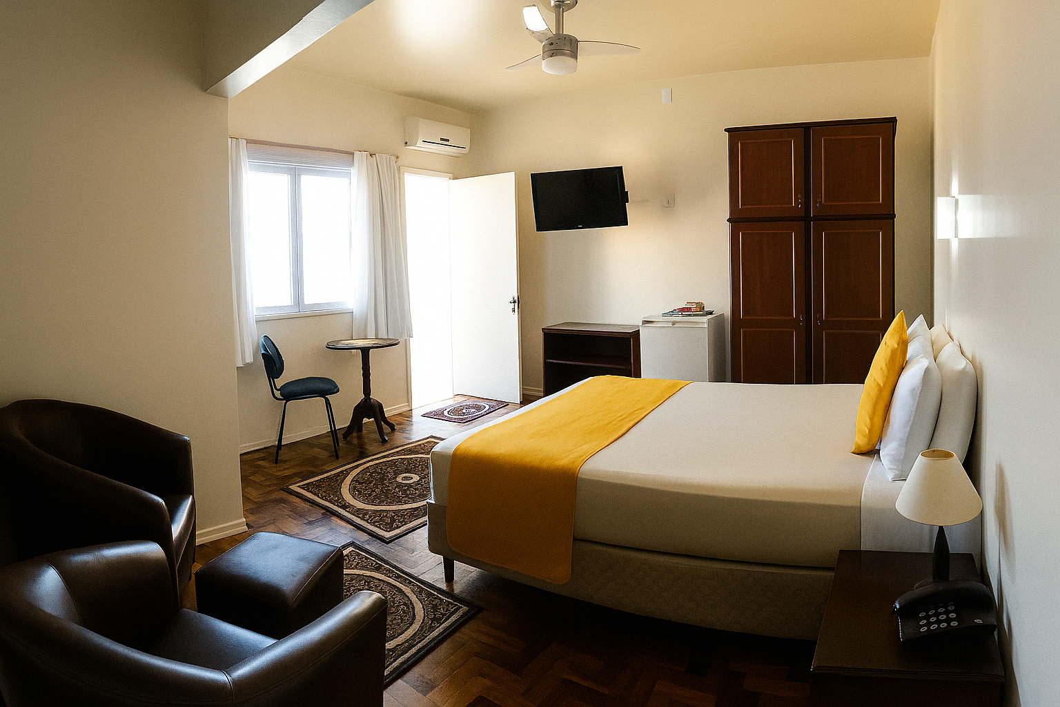 Quarto aconchegante com cama, poltrona de couro, luz natural na janela, TV e tapete estampado.