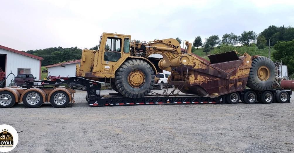 Yellow construction machine on a flatbed trailer, loaded for transport.