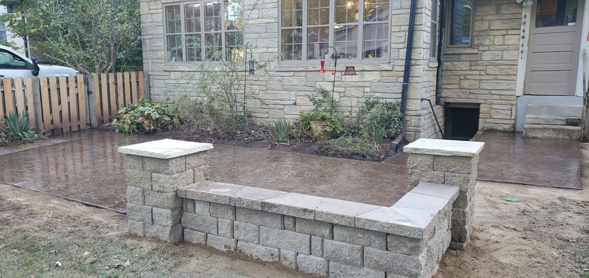 a stone wall is sitting in front of a brick house .